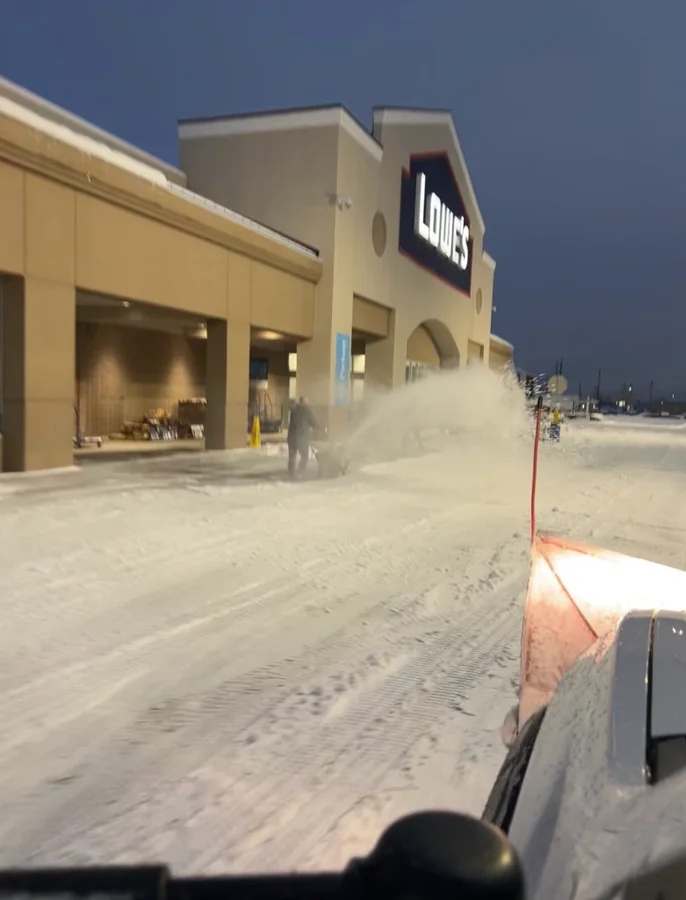 Plowing a big-box store parking lot at dusk